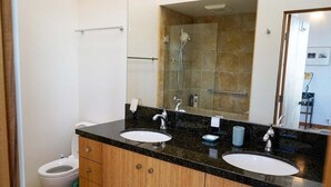 A bathroom with two sinks, a mirror, and a shower area. - Oasis | Ocean Views & Private Hot Tub (Sea Ranch)