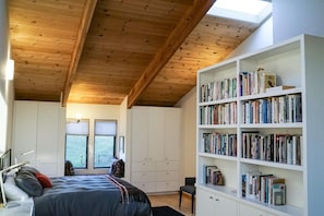 Ein Schlafzimmer mit einem großen Bett, einem Bücherregal und einem Fenster.