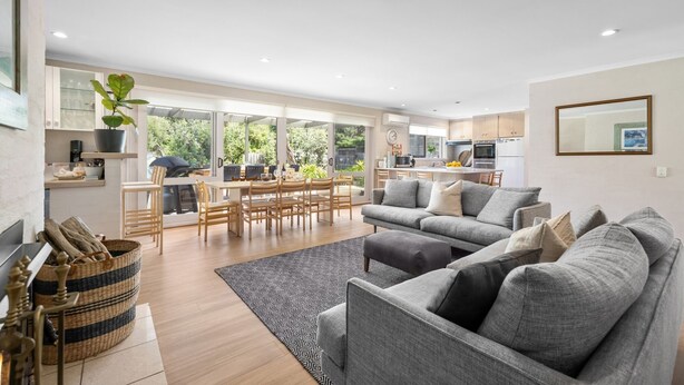 A modern living room with a grey sofa, a dining area with wooden chairs, and a kitchen in the background. - 6 BEDROOM FAMILIES SENSATION, LARGE HOLIDAY BEACH ENTERTAINER IN PORTSEA (Portsea)
