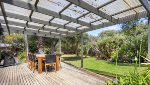 A covered patio with a wooden deck, a table with chairs, and a grill. - 6 BEDROOM FAMILIES SENSATION, LARGE HOLIDAY BEACH ENTERTAINER IN PORTSEA (Portsea)