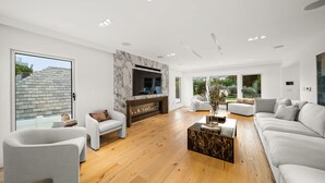 Un salon moderne avec une cheminée, un grand téléviseur et un coin salon confortable.