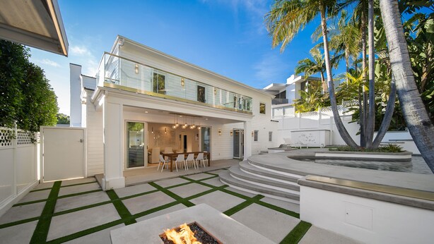 Une maison moderne à deux étages dotée d’un foyer extérieur, d’un espace salon extérieur et d’une piscine.