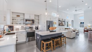 A modern kitchen with white cabinetry, stainless steel appliances, and a central island with bar stools.