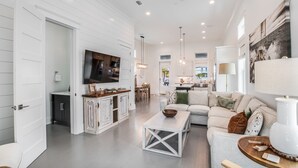 A spacious living area with a sofa, coffee table, and a TV mounted on the wall.