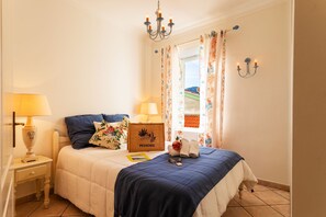 Un lit bien fait, avec une couverture bleue, une tête de lit en bois et une pancarte sur laquelle on peut lire « PROVENCE ».