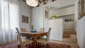A dining area with a wooden table, four chairs, a vase with flowers, and a patterned rug. - Miracoli Apartment with View on the Canal R&R (Venecia)