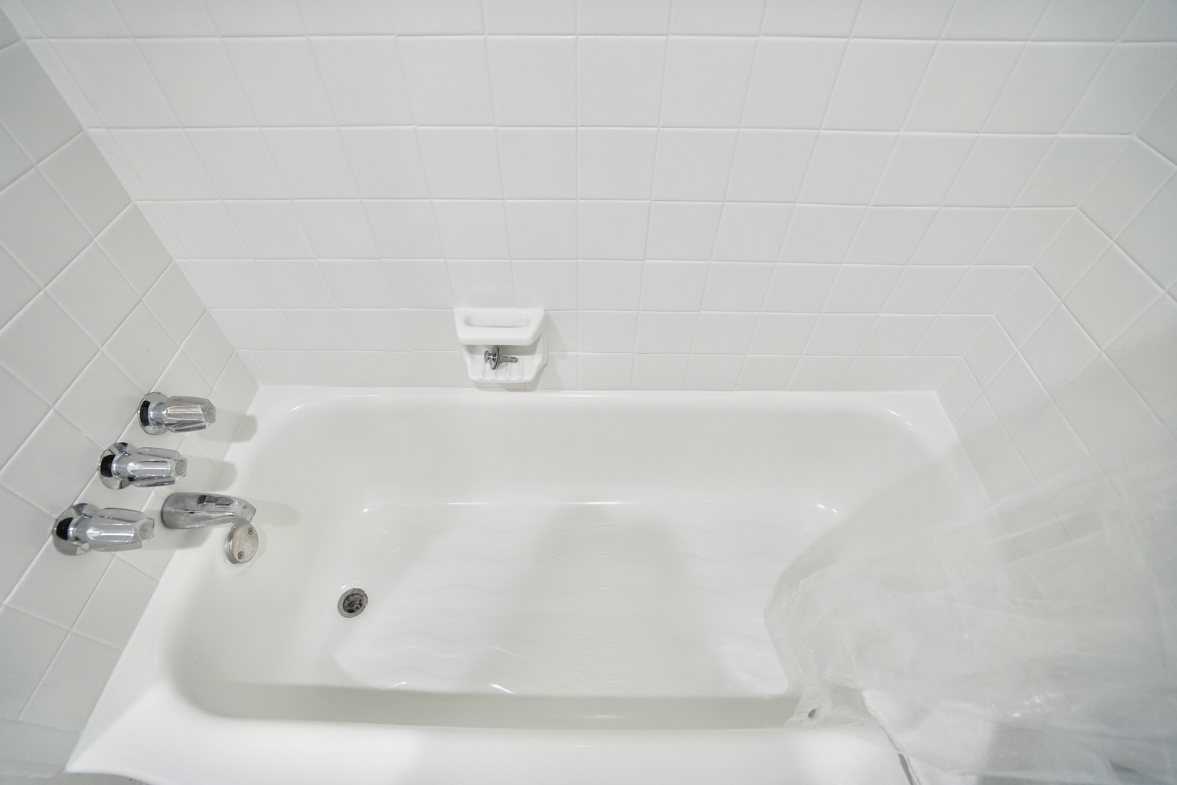 Una bañera blanca con grifería de cromo y desagüe.