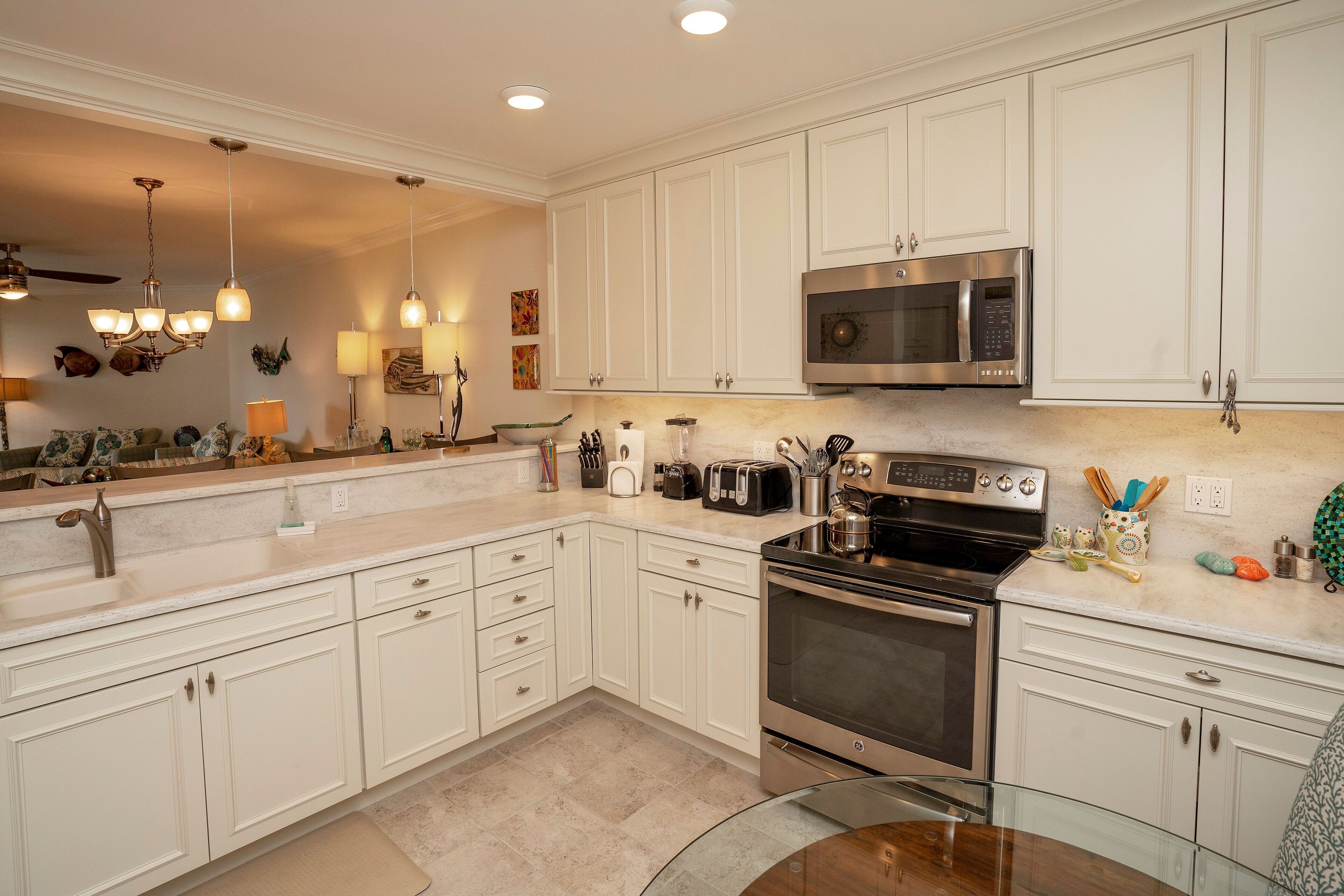 A modern kitchen with white cabinets, stainless steel appliances, and a glass dining table.