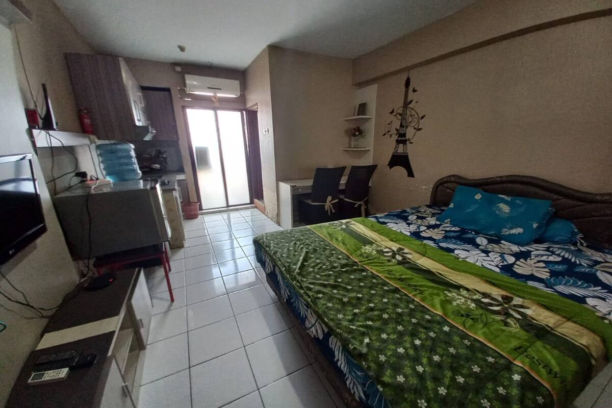 Un dormitorio con una cama, un escritorio, una silla, un televisor y un dispensador de agua.