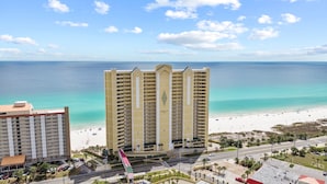 A high-rise hotel with a beach view, a parking lot, and a road with traffic.