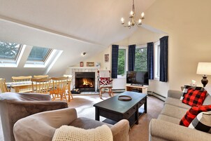 Una sala de estar con chimenea, televisor y comedor con mesa y sillas.
