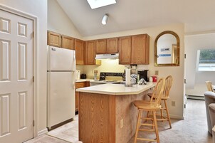 Una cocina con armarios de madera, un refrigerador blanco, una isla integrada con taburetes de bar y una ventana con vistas.