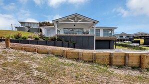 A modern house with a large garage, a covered patio, and a landscaped garden. - Seaglass - Karikari Peninsula Holiday Home (Kaitaia)