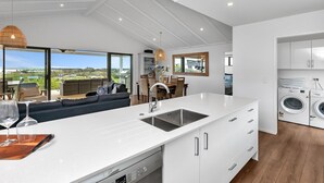 A modern kitchen with a large island, built-in appliances, and a view of the outdoors. - Seaglass - Karikari Peninsula Holiday Home (Kaitaia)