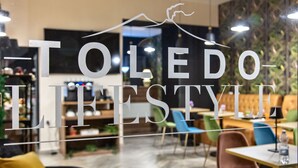 A restaurant interior with a modern design, featuring a glass partition with the text "TOLEDO LIFESTYLE" and a mountain graphic. - Residenza Toledo Lifestyle (Naples)