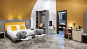 A modern hotel room with a bed, two chairs, a desk, and a wardrobe. - Residenza Toledo Lifestyle (Naples)