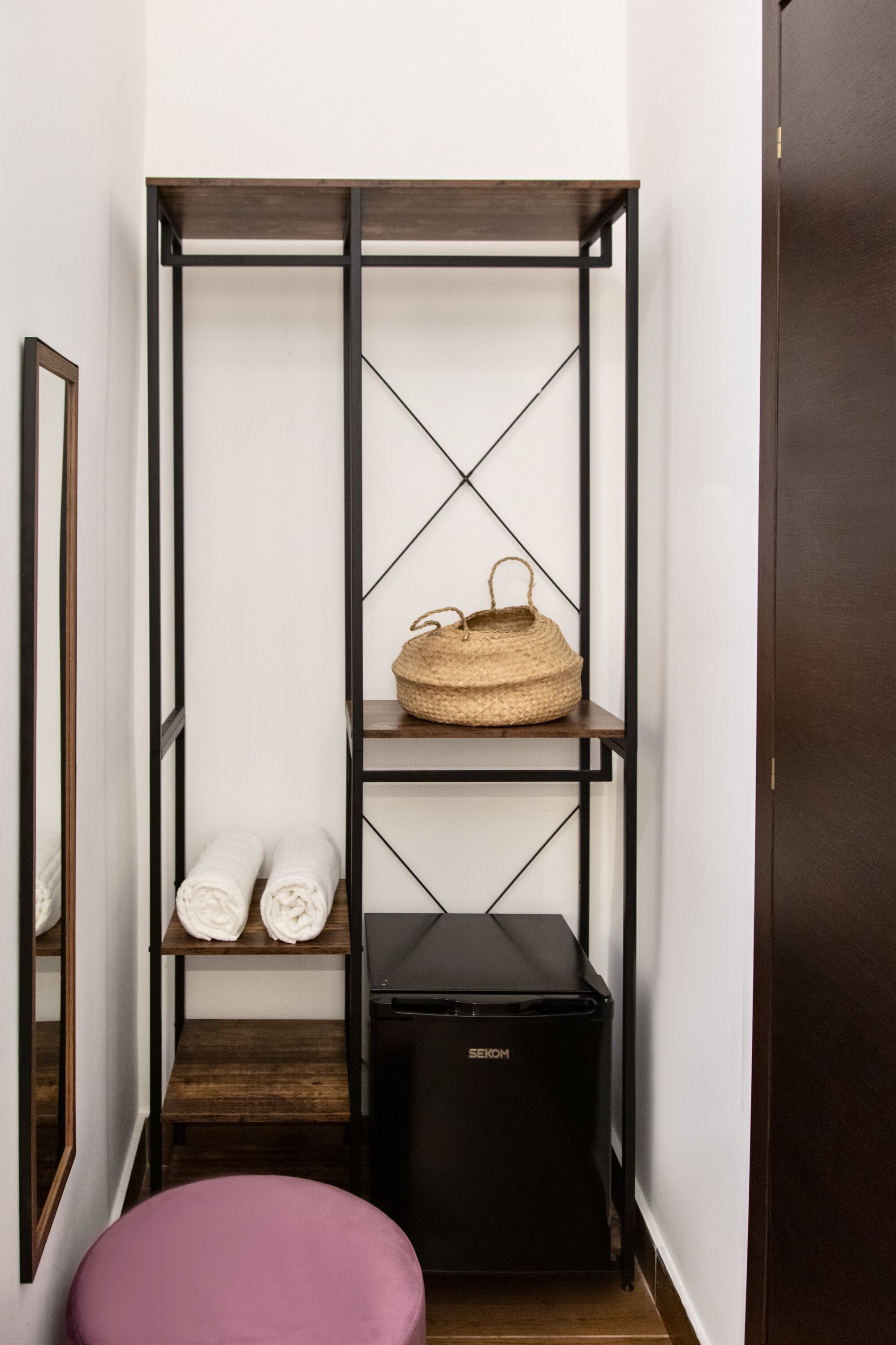 A narrow hallway with a tall, dark metal shelving unit.