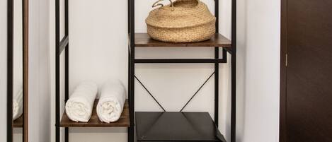 A narrow hallway with a tall, dark metal shelving unit.