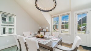 Ein Esszimmer mit hoher Decke, großen Fenstern und einem Chandelier.