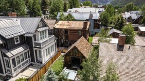 Ein Wohngebiet mit Häusern, die moderne und traditionelle Architektur vereinen, umgeben von üppiger Vegetation und Bergen im Hintergrund.