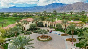 A golf course with a central courtyard, palm trees, and a mountain backdrop. - Private Pool Home in Highly Sought After Mountain View Country Club (La Quinta)