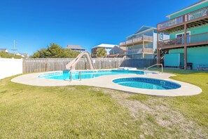 A backyard with a swimming pool, a slide, and a wooden fence. - South Shore Sea Esta - 5 BR Second Row Home - Pool & Kiddie Pool (Surf City)