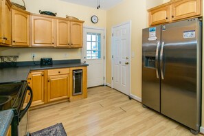A kitchen with wooden cabinets, a stainless steel refrigerator, a microwave, and a window with a view. - South Shore Sea Esta - 5 BR Second Row Home - Pool & Kiddie Pool (Surf City)