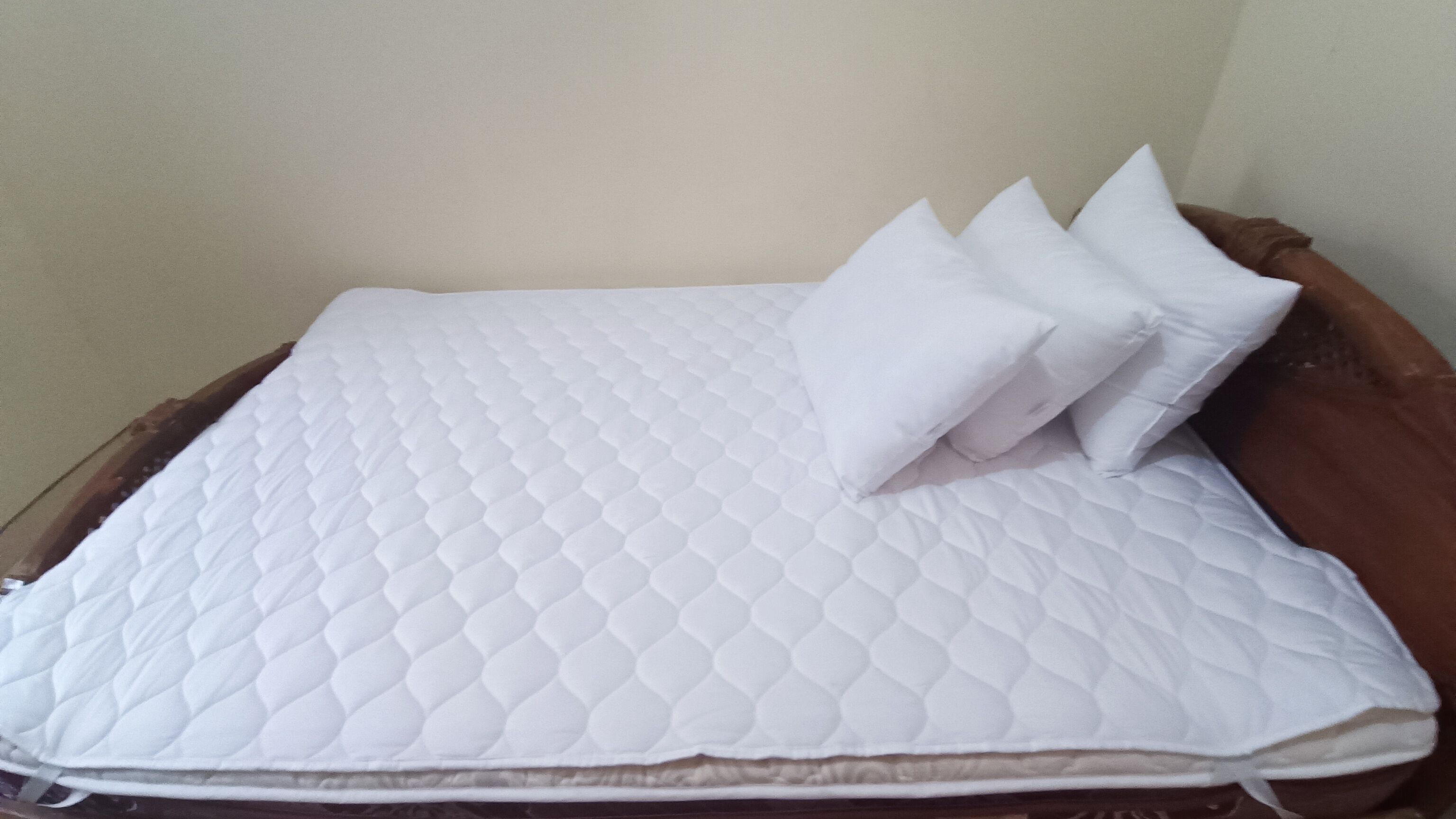 Un lit avec un matelas blanc matelassé et quatre oreillers.