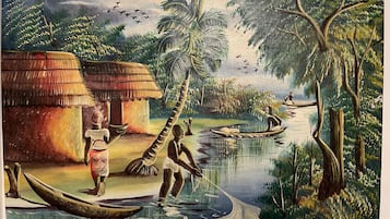 A traditional village scene with huts, a river, and people engaged in daily activities.