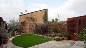 A patio with a green lawn, stone flooring, and a brick wall. - Luxurious Double Studio in London (London)