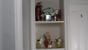 A white shelf unit with various items including a fire extinguisher, vases, and decorative objects. - Luxurious Double Studio in London (London)