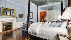 A bedroom with a four-poster bed, a fireplace, and a ceiling fan.