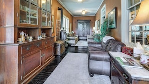 A spacious living room with a fireplace, wooden cabinets, and a large window.