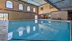 An indoor swimming pool with clear water, a sign reading "The Landing at Eagle's Nest," and a stone wall on one side.