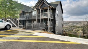 A two-story building with a balcony, a staircase, and a view of the surrounding landscape.