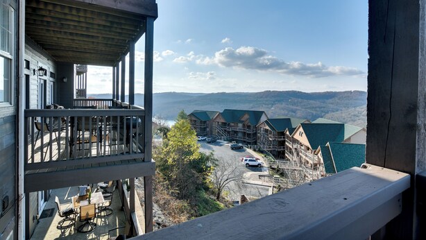 A view from a balcony overlooking a parking area and buildings with a mountainous backdrop.