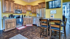 A kitchen with wooden cabinets, stainless steel appliances, and a dining area with chairs.