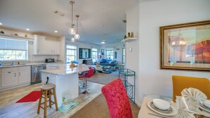 A spacious kitchen with a central island, modern appliances, and a dining area with a red chair and table set.