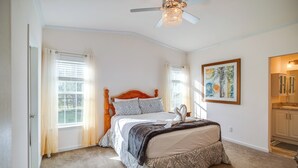 A bedroom with a large bed, a ceiling fan, and a window with curtains.