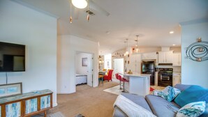 A spacious living room with a sofa, a television, and a kitchen in the background.