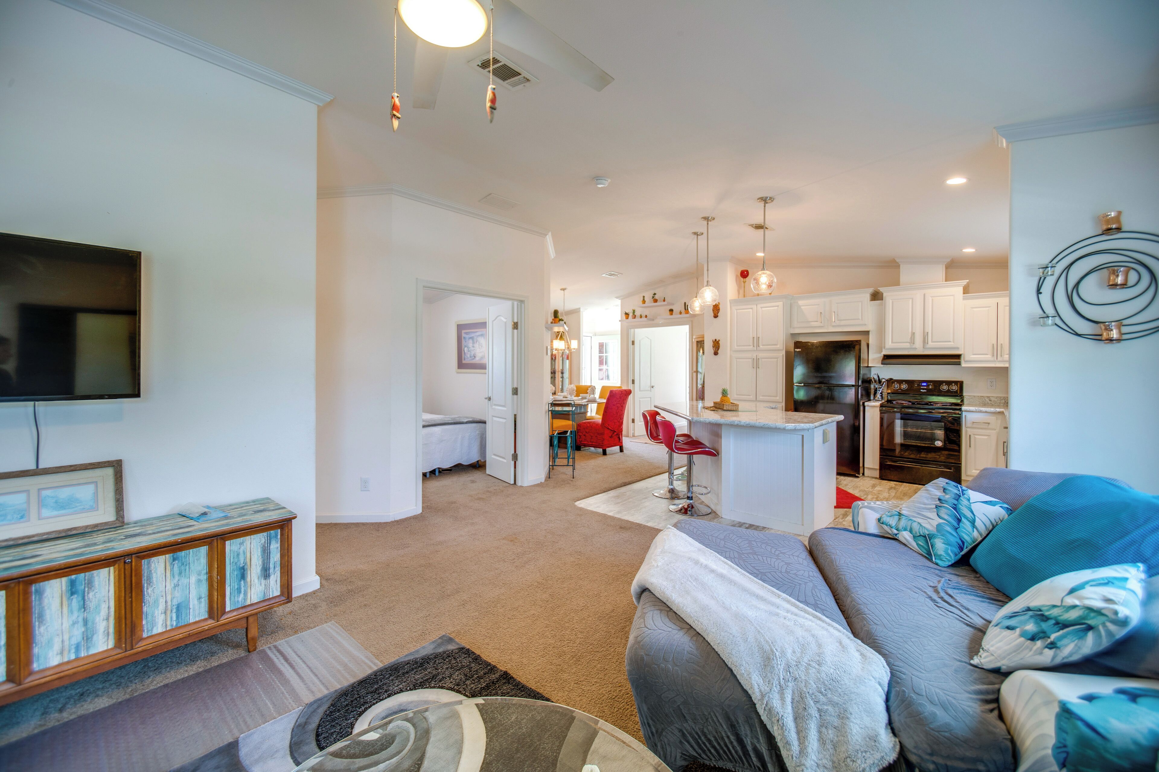 A spacious living room with a sofa, a television, and a kitchen in the background.