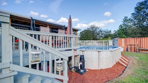A backyard with a pool, a deck, and a shed.