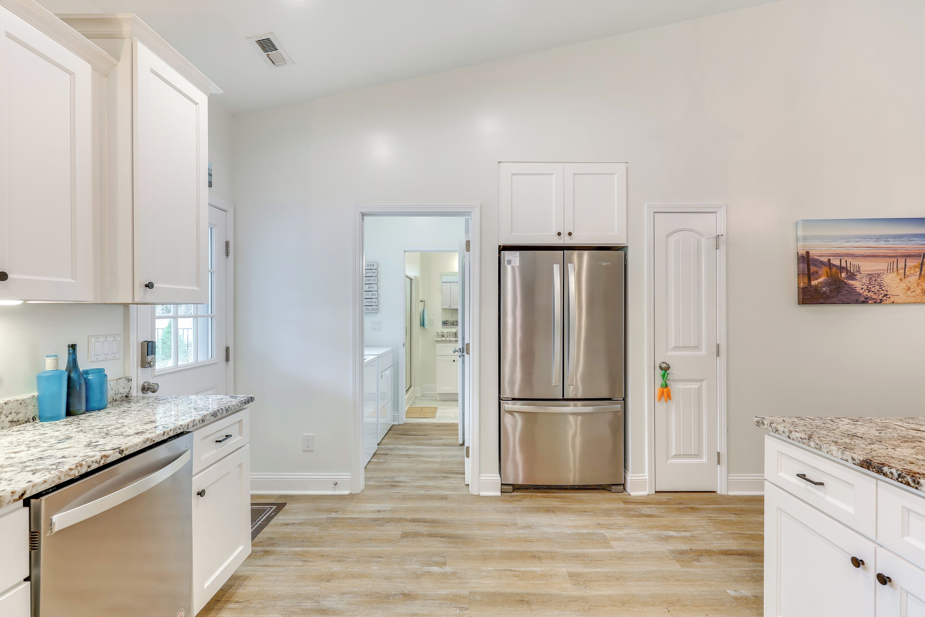 Una cocina moderna con armarios blancos, electrodomésticos de acero inoxidable y suelo de madera.