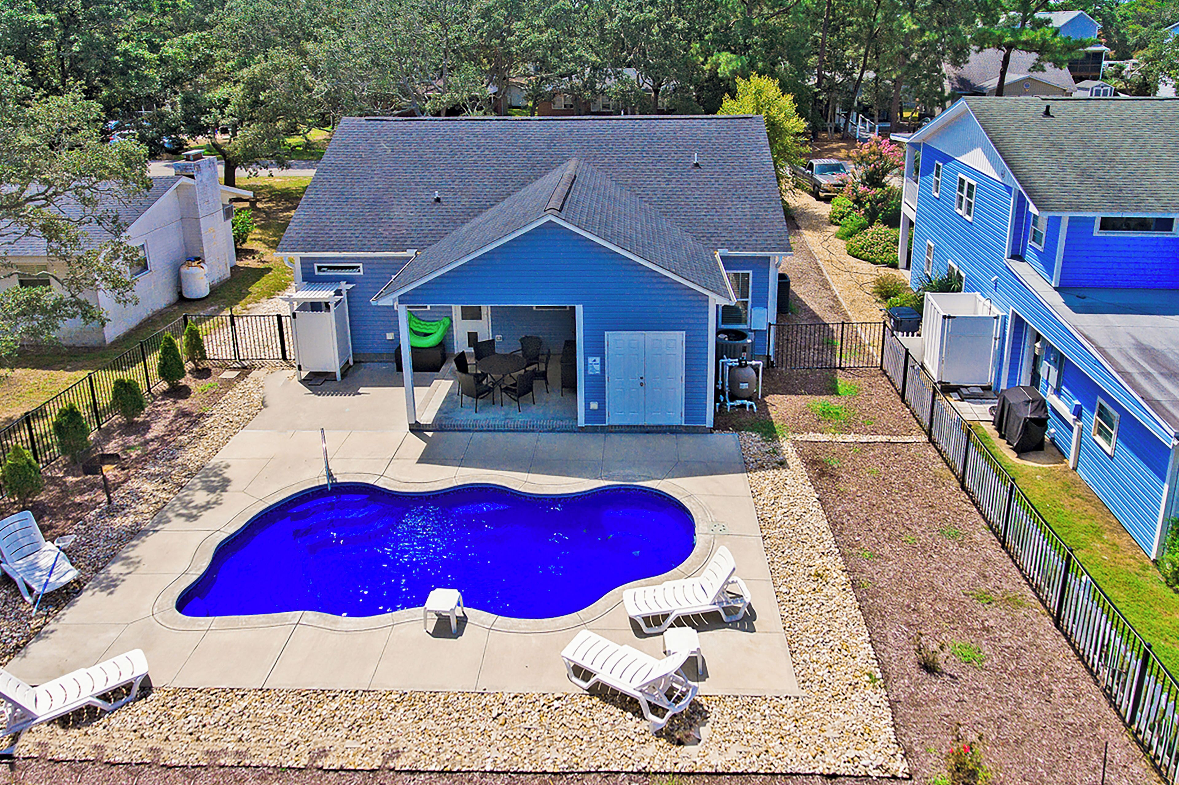 A residential property with a swimming pool, outdoor seating, and a garage.