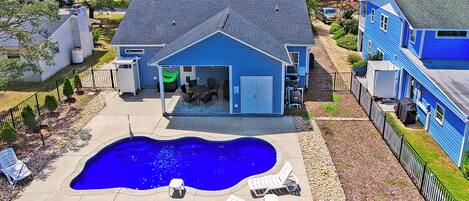 A residential property with a swimming pool, outdoor seating, and a garage.