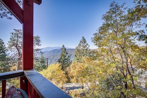 A view from a balcony with a red railing, overlooking a mountainous landscape with autumn-colored trees and a clear blue sky. - Colorful Running Springs Cabin w/ Incredible Views (Running Springs)