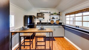 Cocina compacta con una mesa de madera, dos taburetes, un microondas y un refrigerador.