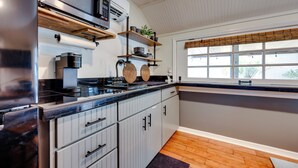 Una cocina moderna con microondas integrado, cafetera y estantes de madera.