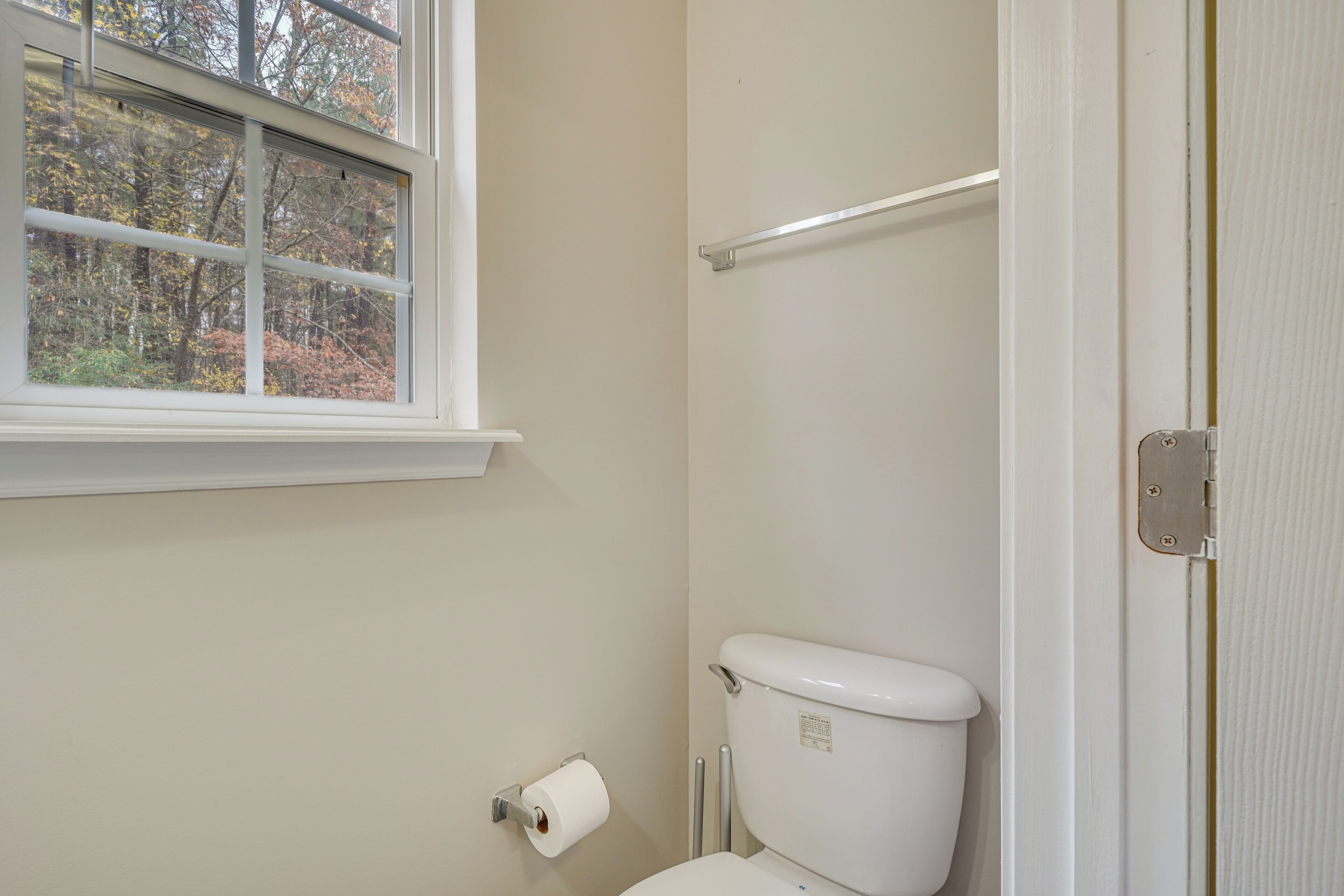 A bathroom with a toilet, a window, and a towel rack.