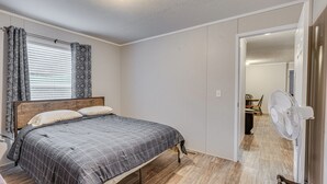 A bedroom with a bed, a standing fan, and a door leading to another room. - Pet-friendly Home ~ 10 Mi to Hocking Hills! (Laurelville)